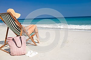 Side view of pretty brunette relaxing on deck chair at the beach