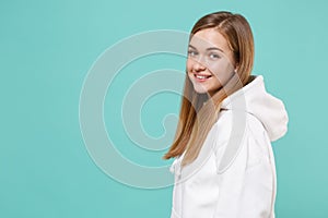 Side view of pretty young woman girl in casual white hoodie posing isolated on blue turquoise background studio portrait