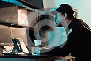 side view of prison guard sitting with cup of coffee and monitoring people