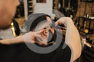 Side view of Professional barber cutting hair of his client.