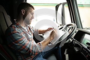 Side view of professional driver behind the wheel in truck's cabin.