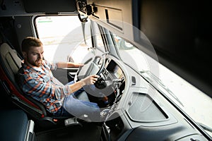 Side view of professional driver behind the wheel in truck& x27;s cabin.