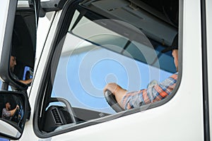 Side view of professional driver behind the wheel in truck's cabin.