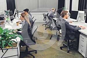 Side view of professional young businesspeople in formal wear working with desktop computers