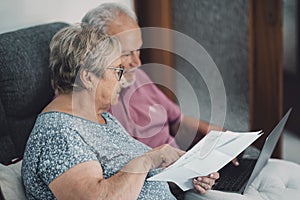 SIde view of real senior couple at home paying bills online with internet banking app and account. Concept of life costs and gas