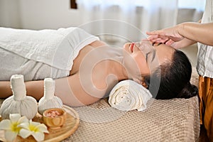 Side view, Relaxed Asian woman getting facial massage, receiving special facial treatment in spa salon