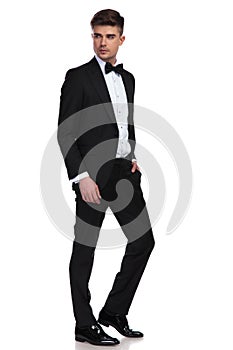 Side view of relaxed businessman in tuxedo looking behind photo