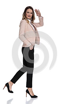 Side view of relaxed businesswoman walking and saluting