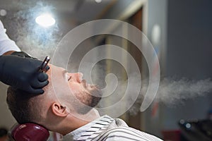 Side view of relaxed man getting haircut in barber shop