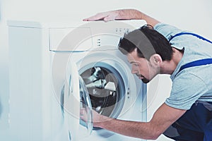 Side view of repairman checking washing machine.