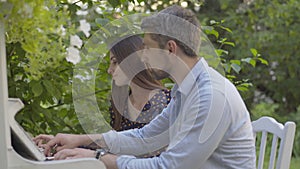 Side view of romantic couple playing piano outdoors on summer day. Portrait of happy beautiful woman and handsome man