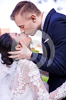 Side view of romantic wedding couple kissing against sky