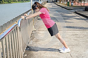 Side view of runner woman doing stretching and warming up her legs before running.