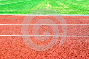 Side view of a running track in a stadium and part of a soccer field with green artificial turf. Background, copy space