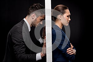 Side view of sad couple in formal wear separated by wall