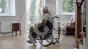 Side view of sad military man in wheelchair looking away thinking. Wide shot of depressed disabled Caucasian retired