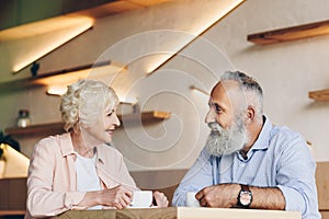 side view of senior couple having conversation while drinking coffee together