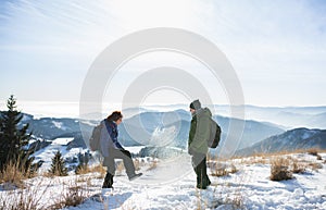 Bočný pohľad na starší pár turistov stojacich v zasneženej zimnej prírode.