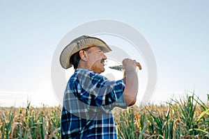 Side view of a senior farmer with a bottle of water in his hand,