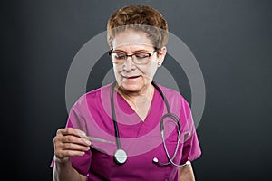 Side view of senior lady doctor looking at thermometer