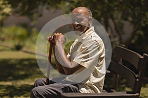 Side view of senior man hands leaning on a cane while sitting on bench