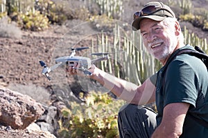 Side view of a senior man holding the drone. One real people with beard and white hair. Game or work activities