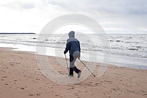 Senior nordic pole walker enjoying nice autumn day outdoors, near sea. active elderly man and woman wearing sport