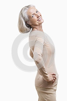 Side view of senior woman in casuals with hands on hips against white background