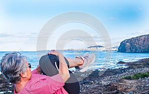 Side view of senior woman doing fitness exercises at the beach. Sport clothing. Horizon over the water