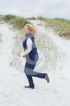 Side view of a senior woman jogging at beach