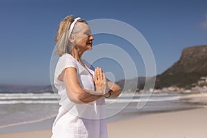 Side view of senior woman meditating in prayer position at beach