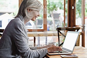 Side view of senior woman using laptop computer while sitting at table