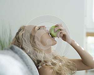 Side view of sensuous woman biting apple in house