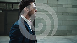 Side view businessman walking in suit. Man wearing sunglasses at street