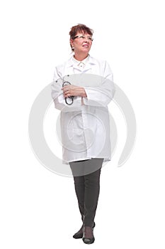 Side view of serious mature woman doctor in a white coat listens with a stethoscope to an invisible object posing on a