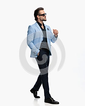 side view of sexy bearded guy looking to side and walking with hand in pocket