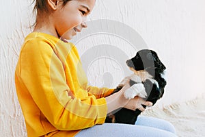 Side view shot of the happy child playing at home with little dog. Pretty little girl cares about the puppy. Kid playing her pet