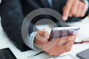 Top view shot of a man`s hands in suit using smart phone in office interior, business man hands using cell phone at