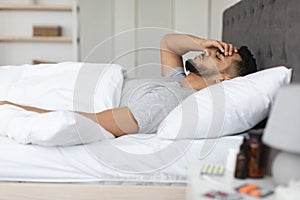 Side View Shot Of Sick Arab Man Lying In Bed At Home photo