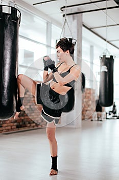 Side view shot of slim woman doing combination of kickboxing elements