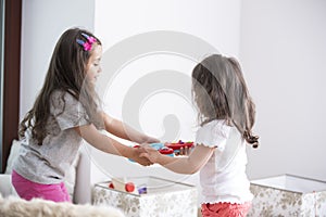 Side view of sisters fighting for toy guitar at home