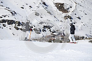 Side view of skiers looking at snow covered mountains