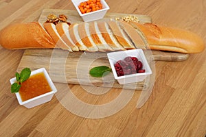 Side view of sliced french bread and three bowl of jam