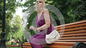 Side view slim elegant gorgeous woman checking time on watch sitting on bench standing up leaving in slow motion