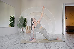 Pretty positive young brunette woman doing Utthita parsvakonasana exercise, yoga and pilates