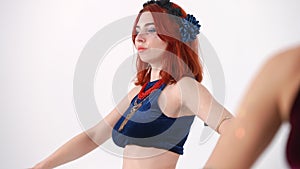 Side view slim woman dancing with female hand moving simultaneously at front. Redhead young Caucasian belly dancer