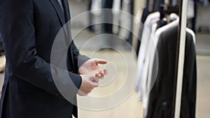 A side view slow motion close up of a business man standing in a clothing shop in front of the mirror and making shure