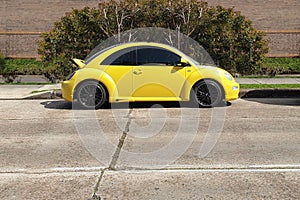 side view of small yellow car parked on street