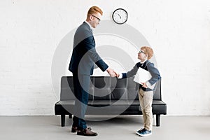 side view of smiling adult and preteen businessmen shaking hands