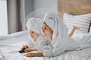 Beautiful caucasian mother and daughter happily watch tv